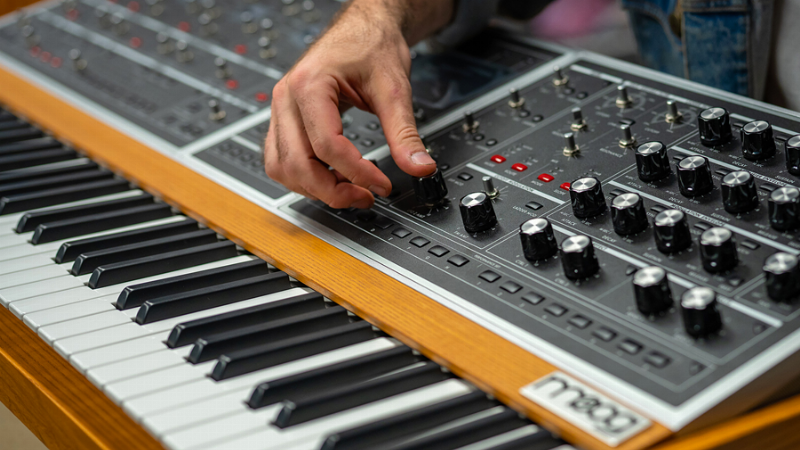 Un chanteur français emblématique des années 80 en studio d'enregistrement avec un synthétiseur vintage